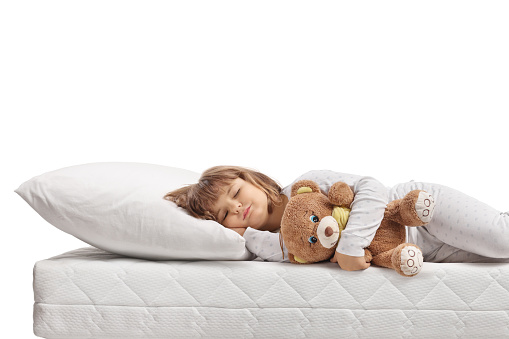 Little girl sleeping with a teddy bear isolated on white background