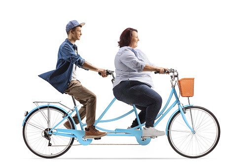 Full length profile shot of a young male and a corpulent woman riding a tandem bicycle isolated on white background