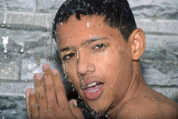 A teenage boy tourist in a wet green T-shirt with stubbed hair looks at the camera.
