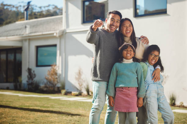 nuevos comienzos: una alegre familia de cuatro abraza el hito de su hogar - common family new togetherness fotografías e imágenes de stock