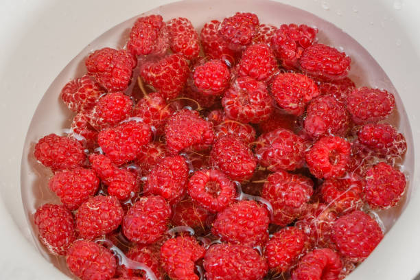 Washing raspberries before eating, running water, bowl, colander, strainer, kitchen sink
