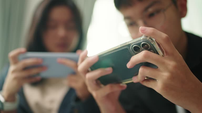 Teenagers playing online game on smartphone together.