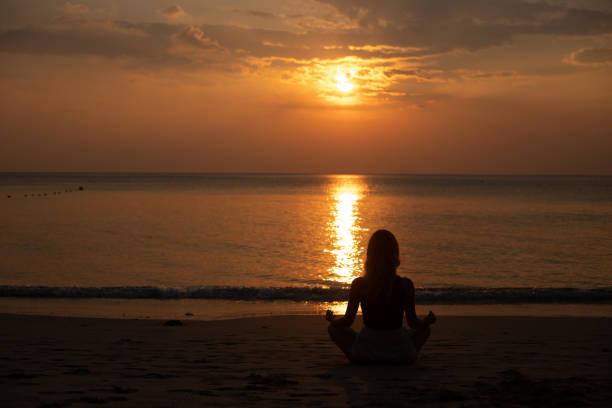 istock Woman meditating on the beach at sunset 1628832844