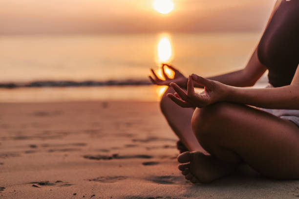 istock Woman meditating on the beach at sunset 1628836602