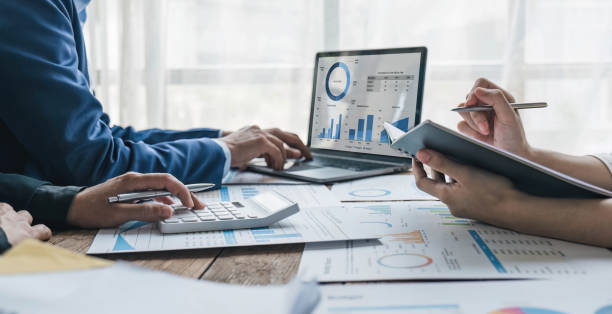 istock Business People Meeting using laptop computer,calculator,notebook,stock market chart paper for analysis Plans to improve quality next month. Conference Discussion Corporate Concept. 1628849876