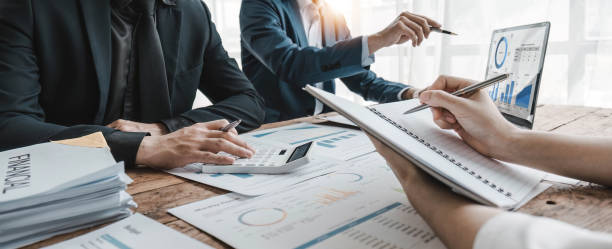 istock Business People Meeting using laptop computer,calculator,notebook,stock market chart paper for analysis Plans to improve quality next month. Conference Discussion Corporate Concept. 1628850445