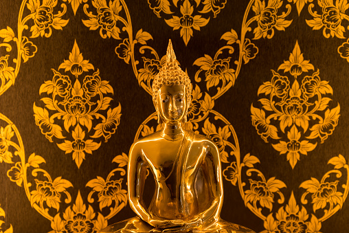 Buddha statue with warm lighting decoration in Thai house for praying. Religion, lifestyles concept.