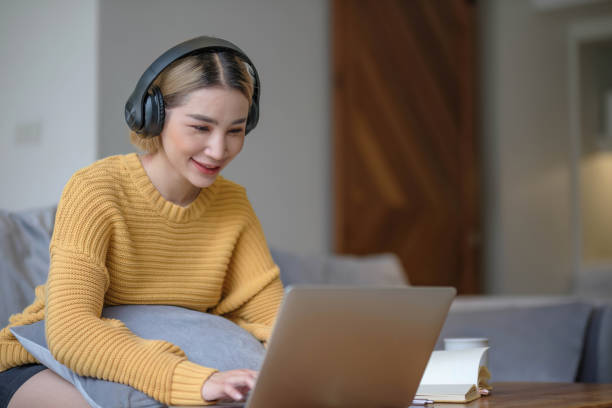 istock young asian woman student with headphones using laptop in a video call or online class while sitting on sofa at home 1628853869