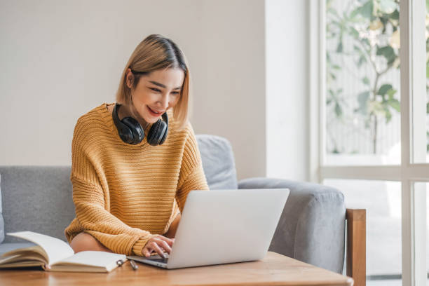 istock young asian woman student with headphones using laptop in a video call or online class while sitting on sofa at home 1628853888