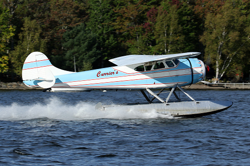 A vintage 1948 Cessna 195 aircraft on floats, operated by Currier's Flying Service taking off from Moosehead Lake, Greenville, Maine, USA.