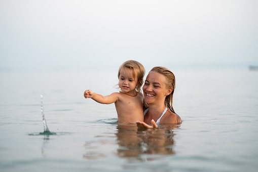 Happy single mother and her small daughter enjoying in sea during summer