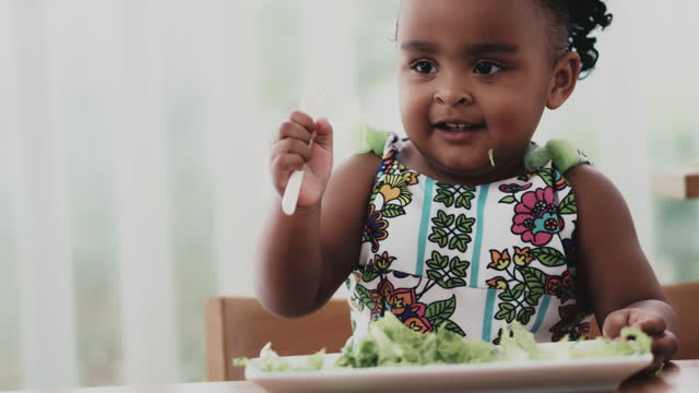 African baby girl eating vegetable salad
