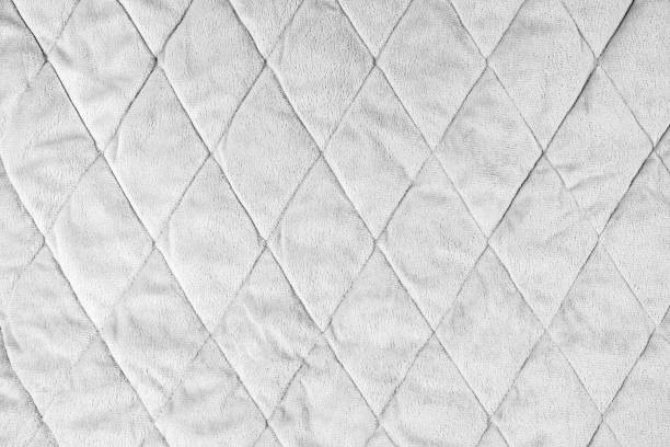 istock Quilted white velours fabric background, wrinkled soft blanket surface 1628880648