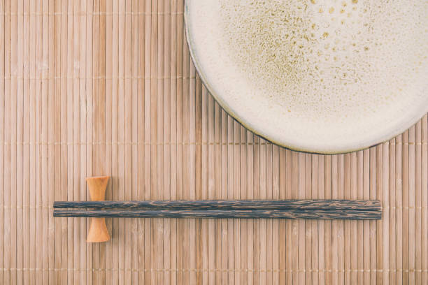 istock Flat lay blank handmade ceramic dish plate and chopsticks on Japanese bamboo mat background. 1628881166