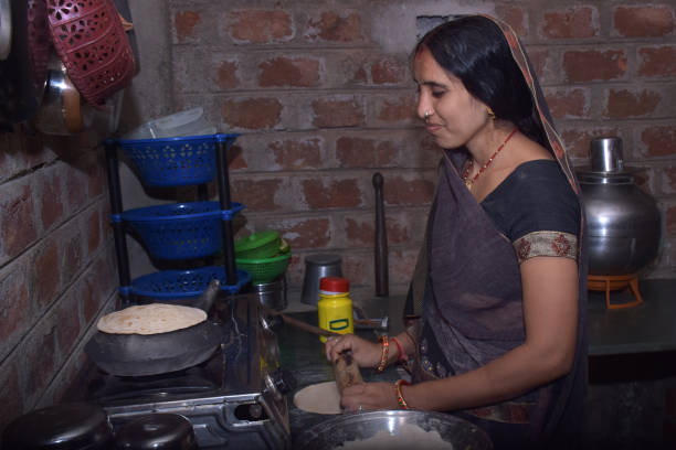 istock An Indian rural housewife while cooking Bread(roti) in an earthen pot using LPG gas, kitchen concept, cook house, brick wall background 1628898435