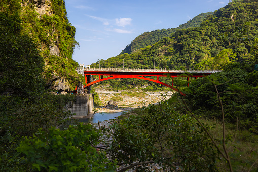Shakadang bridge over the Liwu River at the entrance of the Shakadang Trail, one of many stunning hiking trails in the Taroko National Park Taiwan. The red steel bridge cross the crystal clear stream