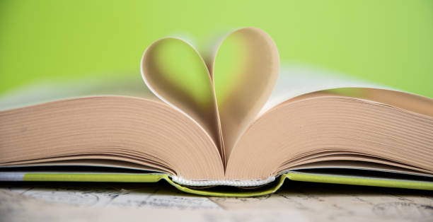 istock Heart from a book page on green background 1628917133