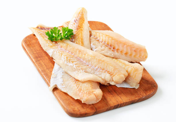 Fresh fish fillets on a cutting board Studio shot of fresh fish fillets haddock stock pictures, royalty-free photos & images