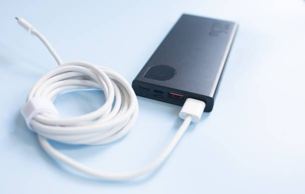 istock Black aluminum power bank with USB cable on blue background. 1628929705
