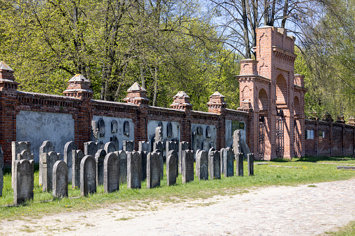 Lodz, Poland - May 4, 2023: Lodz Jewish Cemetery,  tombstones and mass graves of victims of the Lodz Ghetto. Lapidarium and the red brick wall with Internal gate