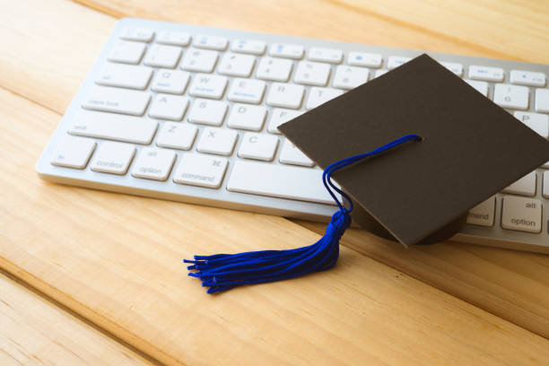 istock Graduation cap and keyboard computer on wooden table backgrounds. 1628947476