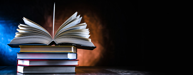 A composition with an open book lying on a stack of other books