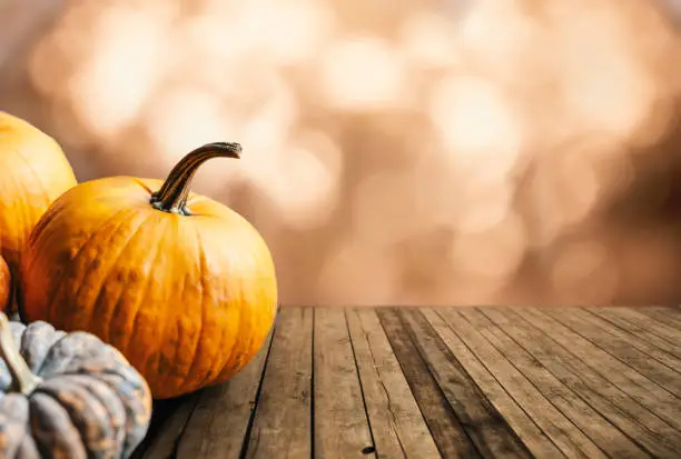Photo of Thanksgiving pumpkins still life on vintage wooden table and bokeh background.