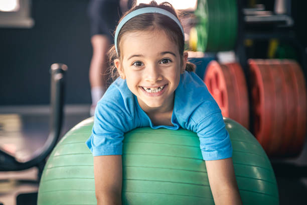 Happy girl stretches her body on a fitball in the gym. stock photo