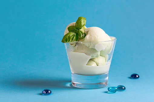 Basil ice cream in serving glass, decorated with fresh basil leaves. Copy space. Concept of summer desserts.