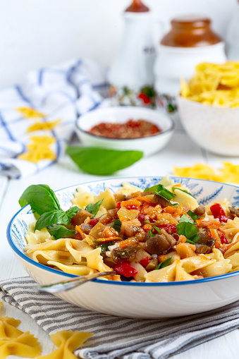 Farfalle pasta with vegetable sauce is served with fresh basil. Concept of vegetarian nutrition.