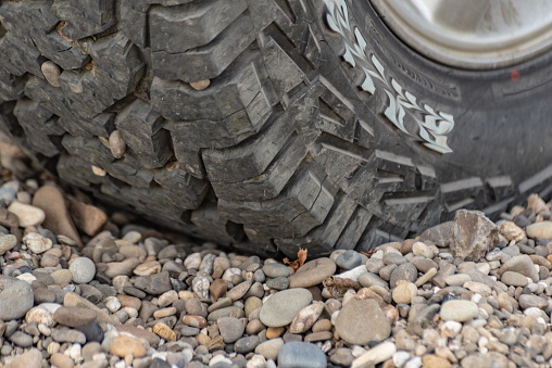 Off-road mud tires on the shore with pebbles