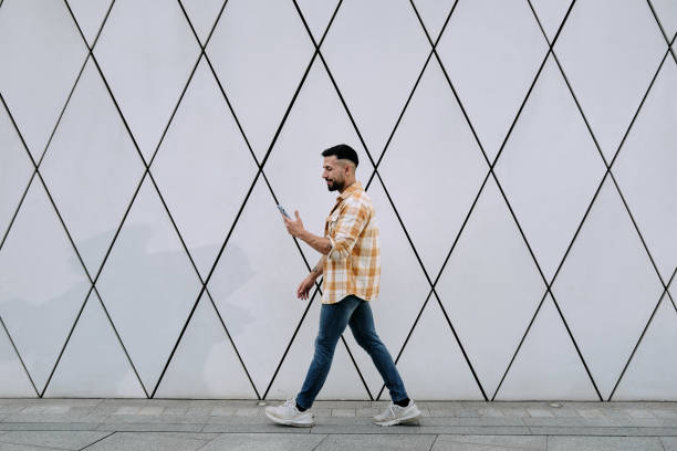 istock A young man using phone as he walks past a tall city building 1629014198