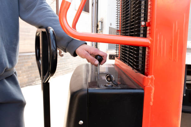 istock employee using the automatic hydraulic trolley lifter or forklift on the production delivery 1629032040