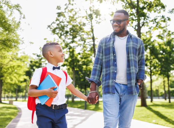 istock Schoolboy looking at father with smile while going with dad to first grade in school on sunny autumn day 1629034938