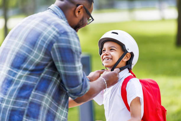 istock Happy family: father puts on son helmet for safe cycling in park 1629038820