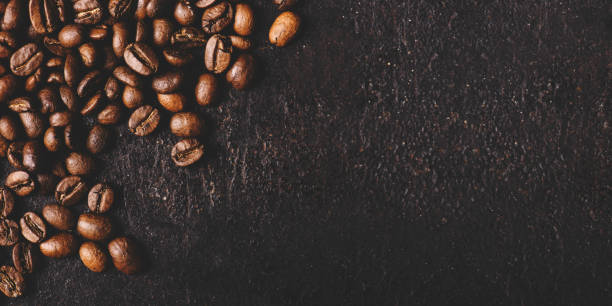Coffee beans on rustic black background from above. Coffee shop creative menu design layout.