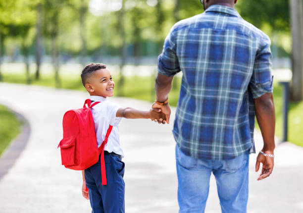 istock Schoolboy looking at father with smile while going with dad to first grade in school on sunny autumn day 1629049175