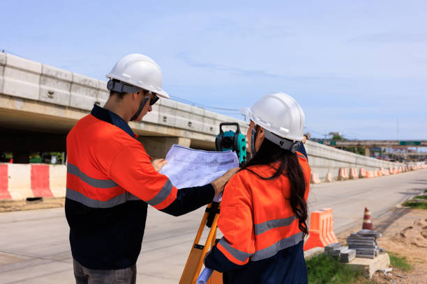 istock Engineer use theodolite equipment and looking blueprints construction project for route surveying to build a bridge across the intersection to reduce traffic congestion during rush hours 1629061014