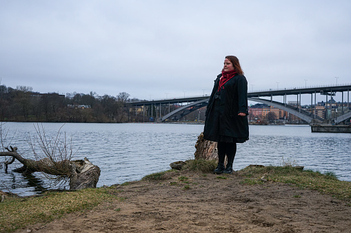 Woman standing by river against sky