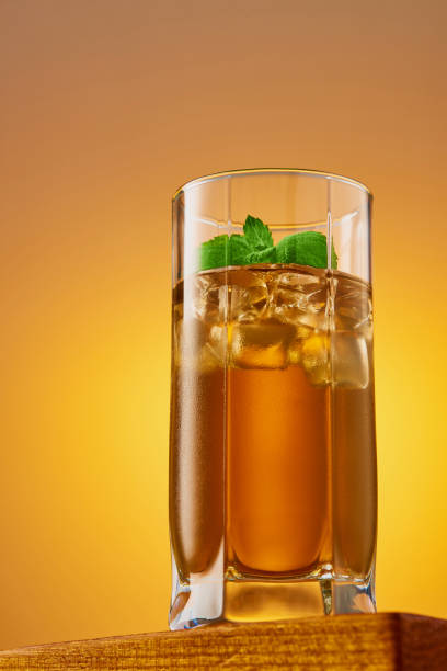 アイスキューブとミントの葉が入ったさわやかなアイスティーのグラス。ローアングルからのスタジオショット。垂直フレーム。 - green tea ice tea ice cube mint ストックフォトと画像