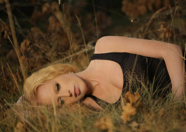 A blonde woman lying in a autumn forest
