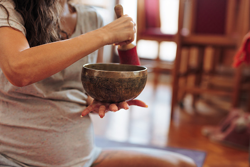 Spiritual pregnant woman using a Tibetan singing bowl as an alternative medicine to meditate and increase relaxation