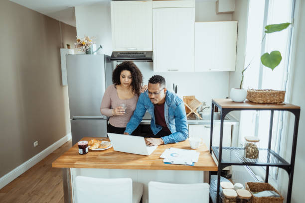 istock Serious Afro Caribbean couple at home, using internet on laptop to make financial decisions 1629106543