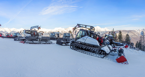 Panoramic slope snow removal equipment for a ski resort. Snow plowing bulldozer grooming for skiing and snowboarding holidays on mountain