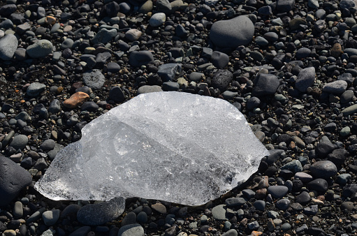 Melting chunk of ice on a black stone beach in the south of Iceland.