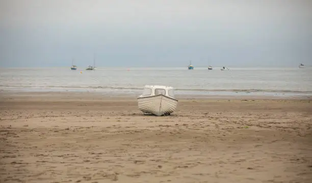 Small isolated white boat marooned on the sands awaiting another high tide to get afloat.