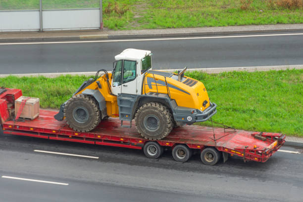 istock Truck with a long trailer platform for transporting heavy machinery, loaded tractor with a bucket. Highway transportation. 1629130618