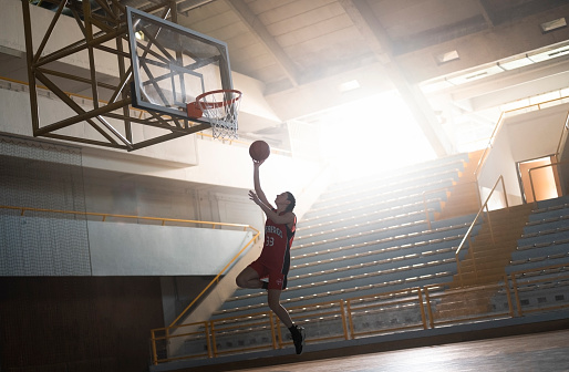 In fly. Full length portrait of young basketball player in uniform on gradient studio background. Teenager confident posing with ball. Concept of sport, movement, healthy lifestyle, ad, action, motion.