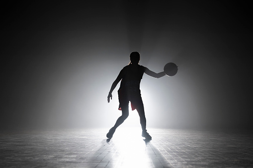 Female basketball player dribbling while playing basketball on sports court during practice.