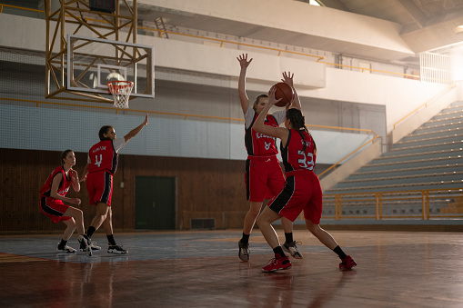Female basketball player throwing basketball towards hoop to score during practice on court.